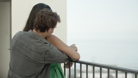 Beautiful-multiracial-couple-standing-at-balcony,-hugging.
